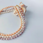 Trois colliers en perles d'eau douce posés sur un coquillage sur fond blanc. 